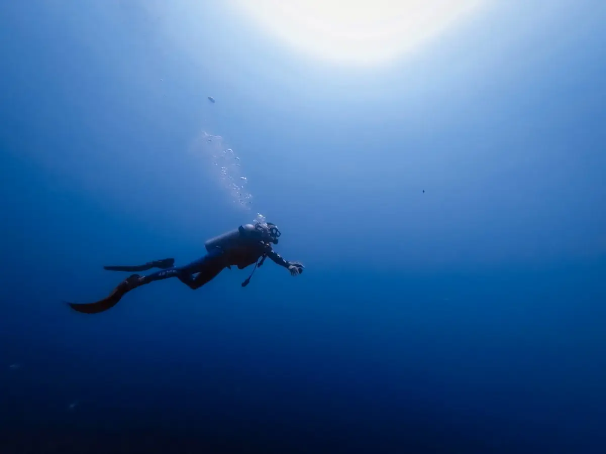 A freediver descending over a reef slope in clear tropical water